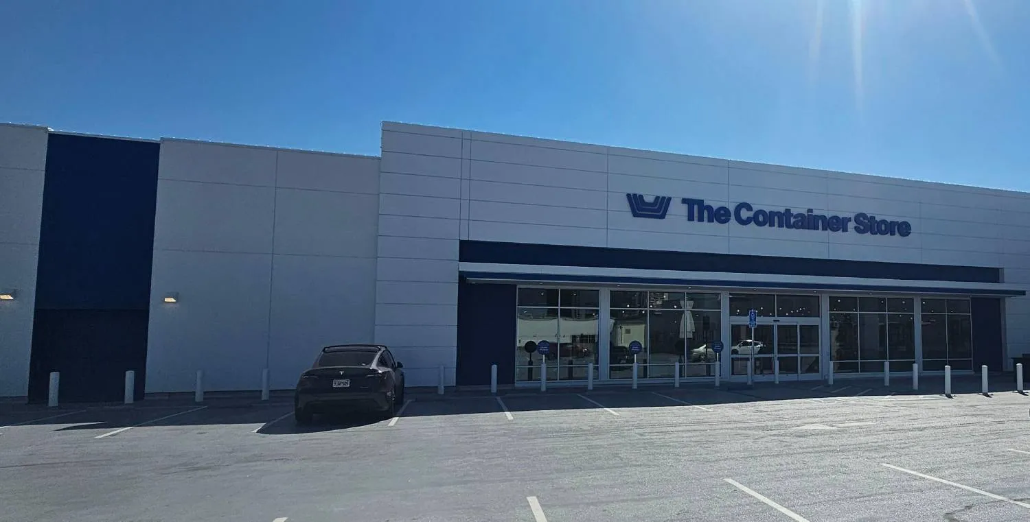 Exterior view of The Container Store with white plaster finish and parking lot.