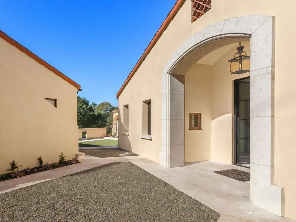 Mediterranean-style building with stucco walls and stone archway under a blue sky.