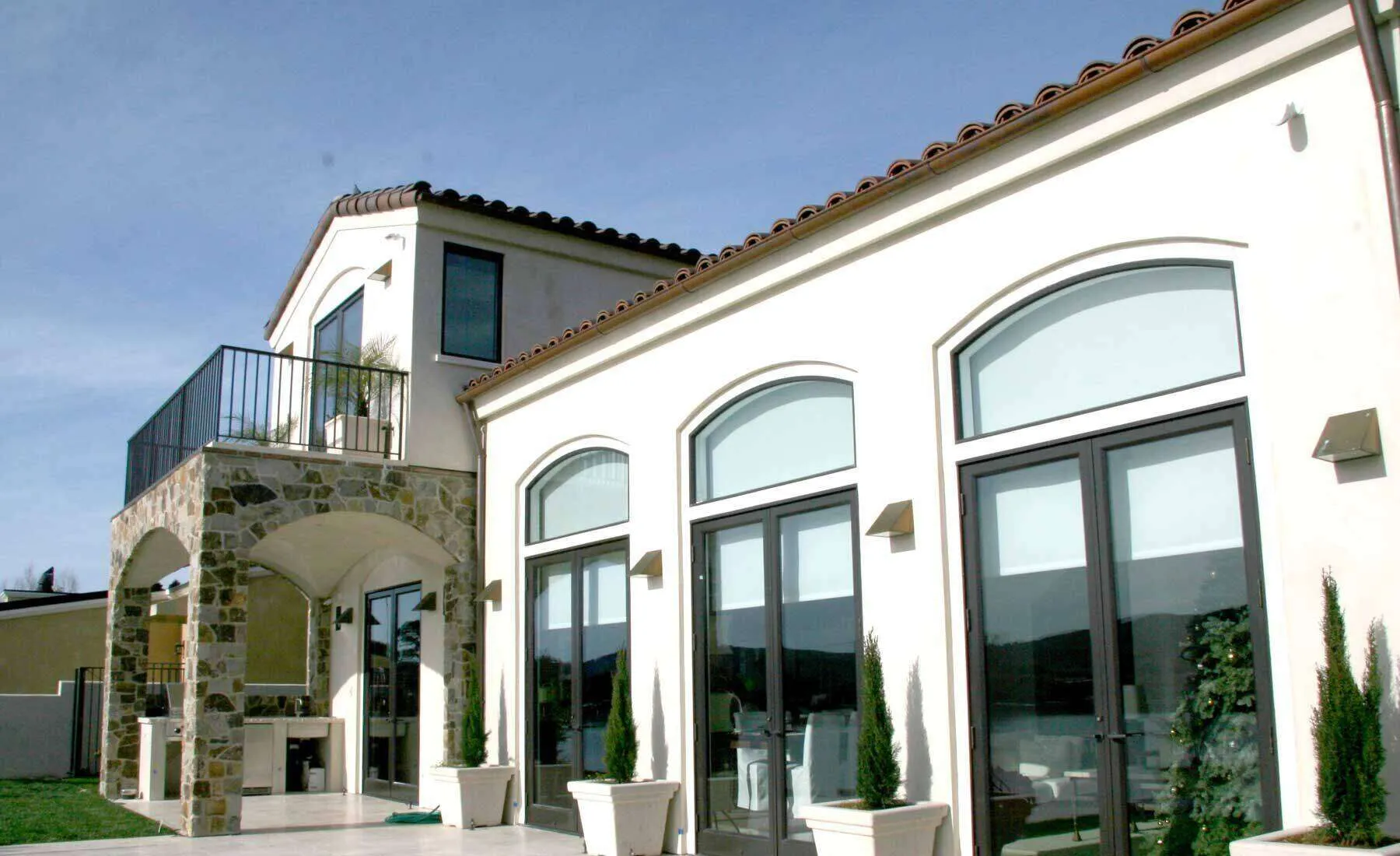 Modern two-story house with stucco exterior, stone accents, large windows, and balcony.