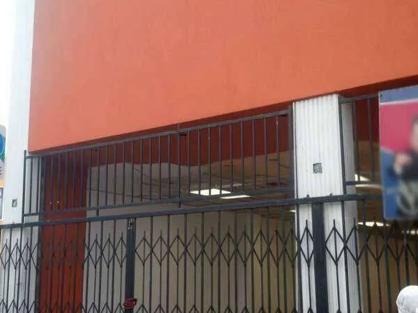 Commercial storefront in Oakland with orange EIFS stucco and metal security gates.
