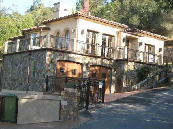 Two-story home in Oakland with stucco and stone exterior, large windows, and balcony.