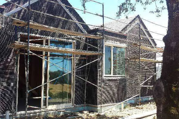 House under construction with scaffolding and lath on exterior walls, ready for stucco.