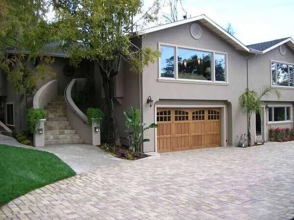 Two-story stucco home with wooden garage door and curved staircase in Greenbrae.