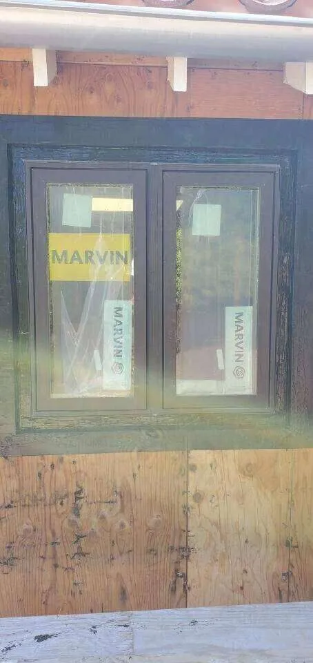 Window installation with Marvin windows, plywood, and waterproofing preparation visible.